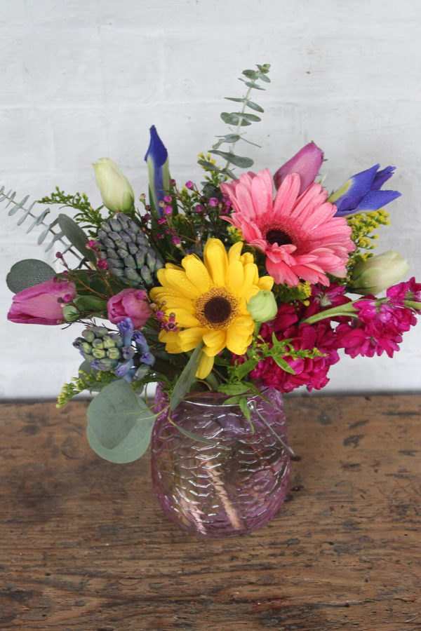a brightly colored arrangement with yellow, pink, and blue flowers